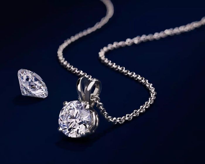 Loose diamond beside a diamond pendant necklace with silver chain